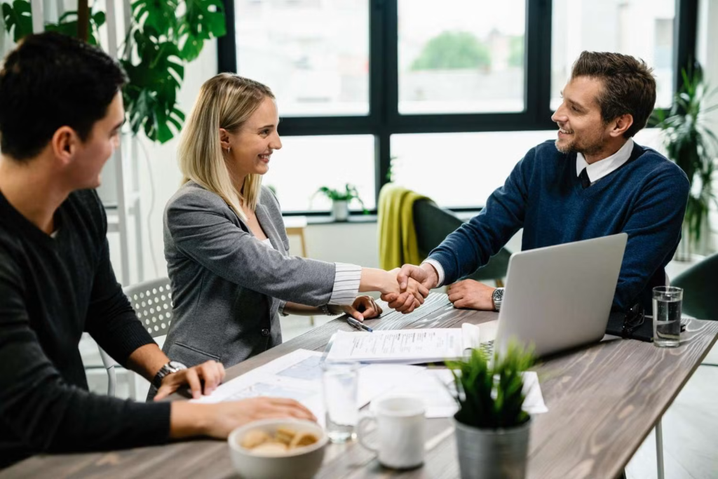 young happy couple meeting with financial advisor office woman is handshaking with agent 1 1