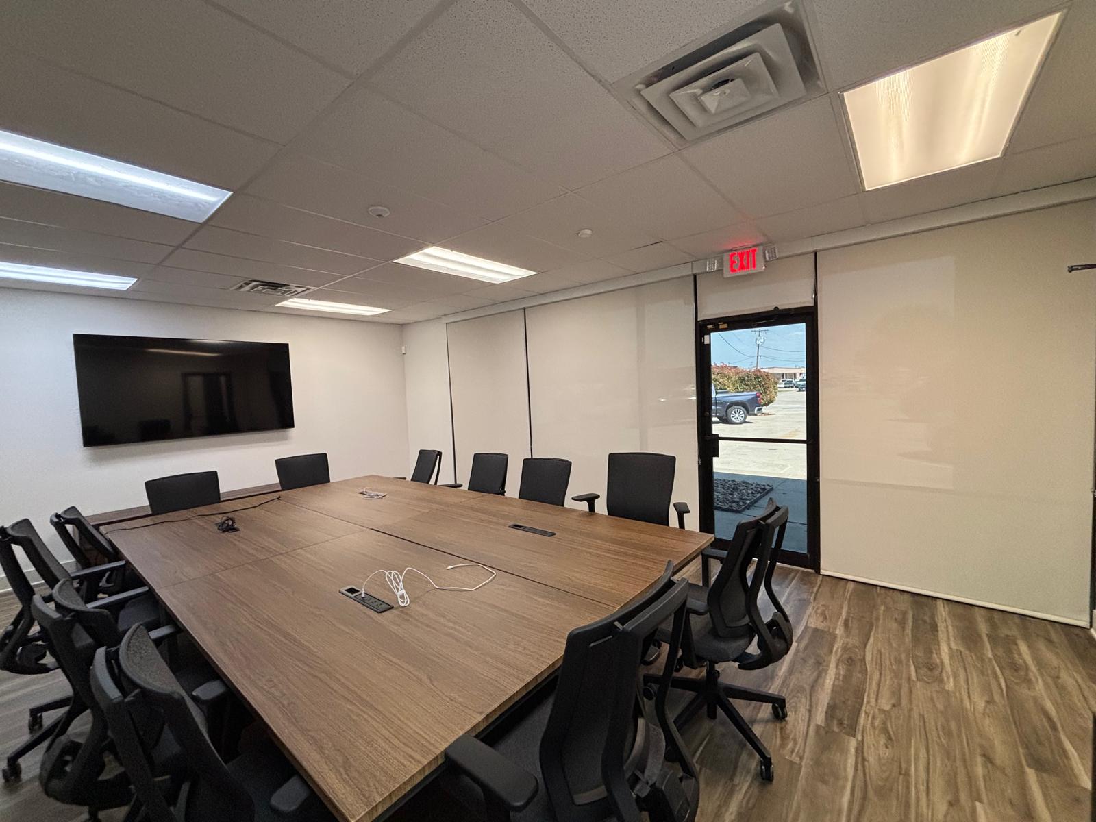 Conference room with white solar roller shades lowered over a window wall