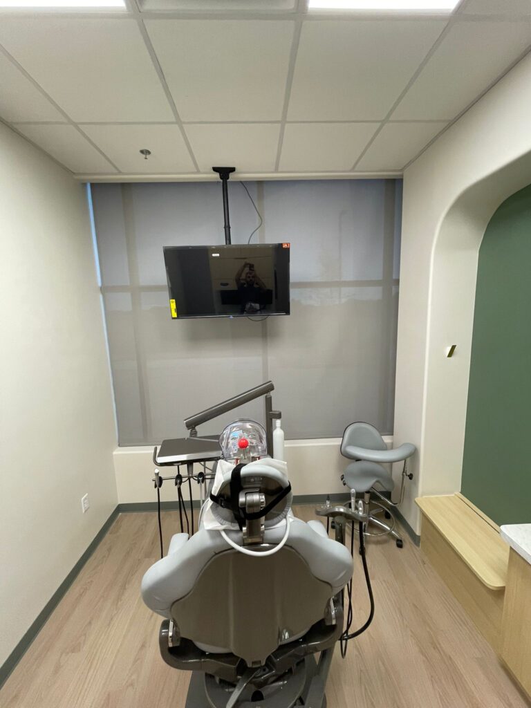 Solar roller shade in a dental exam room with a ceiling-mounted TV