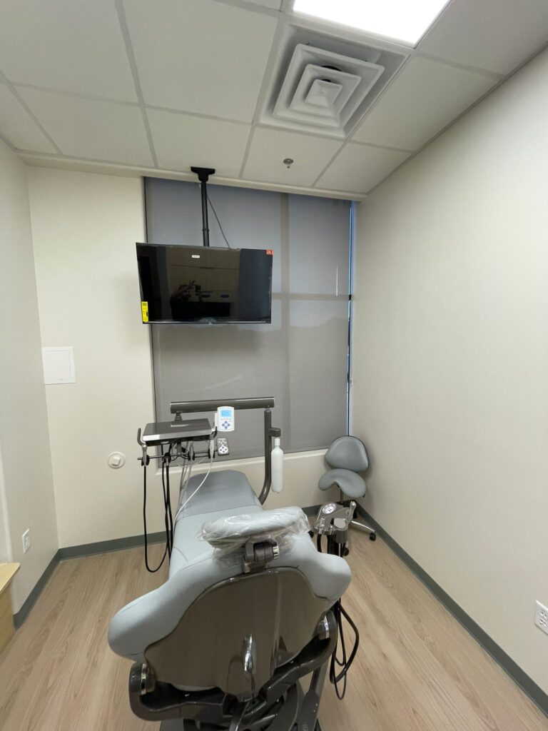 Solar roller shade lowered behind a dental chair in an operatory