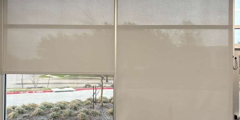 Solar roller shades partly lowered behind office lobby seating