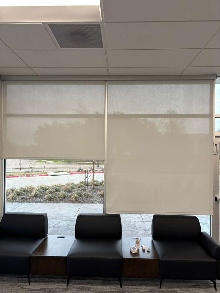 Solar roller shades partly lowered behind office lobby seating