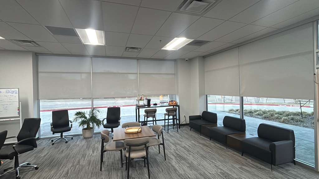 Office lounge with light-filtering roller shades on two window walls