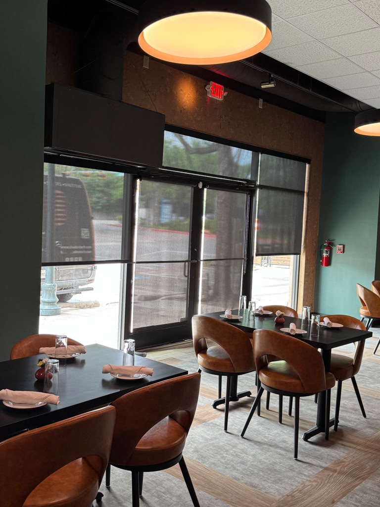 Solar roller shades over a restaurant entry and storefront windows