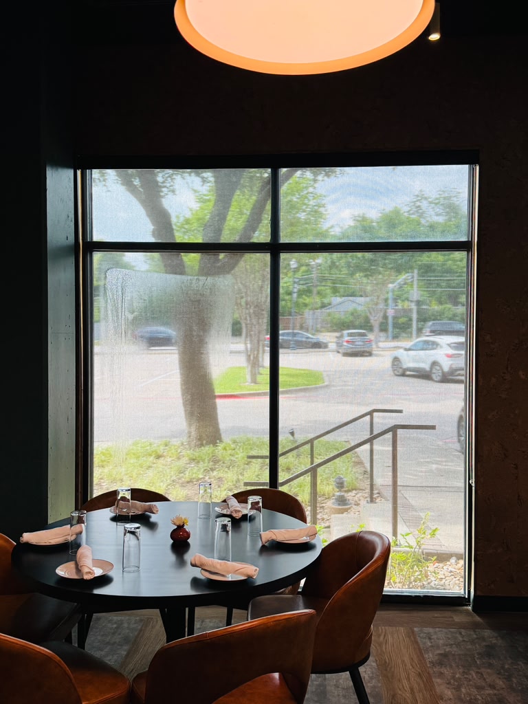 Solar screen shade lowered beside a set restaurant table