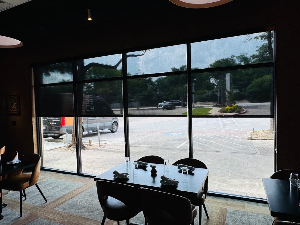 Solar roller shades lowered across a restaurant window wall