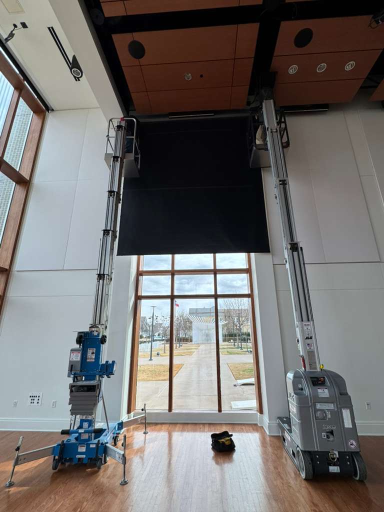 Shadeotech team installing a tall blackout shade with lifts in a public building