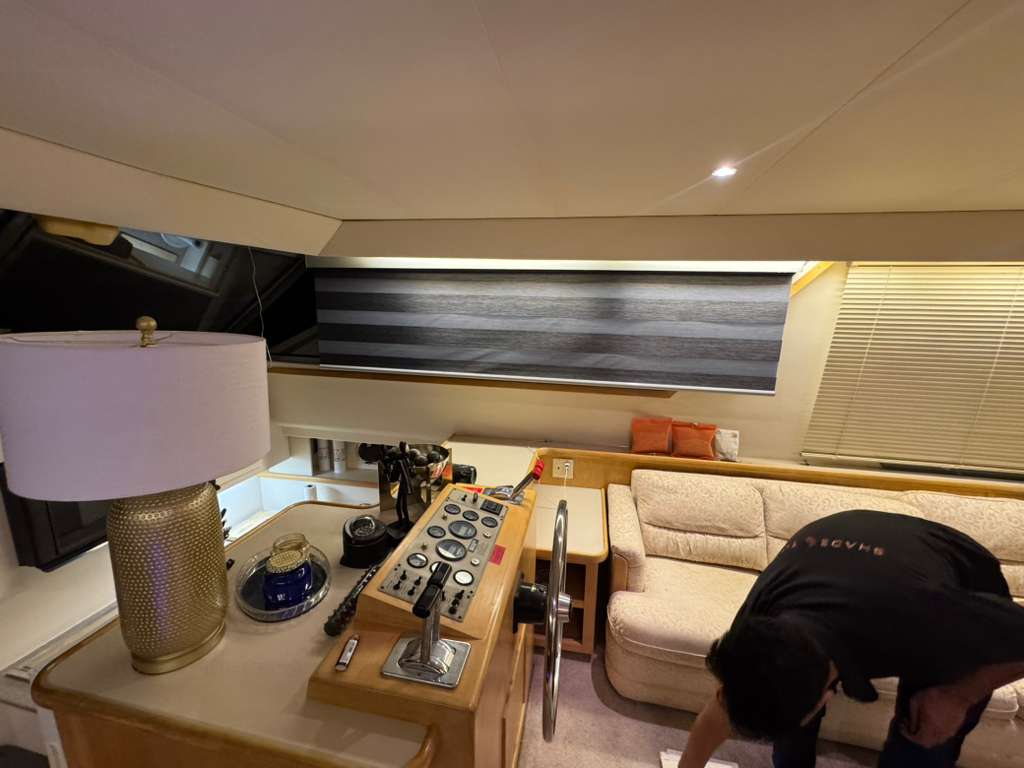 Shadeotech installer fitting a custom shade beside a yacht helm station