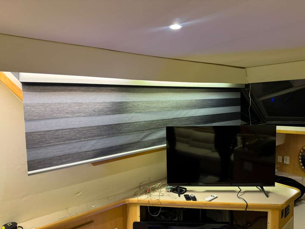 Duo zebra shade on a yacht salon window above a TV cabinet